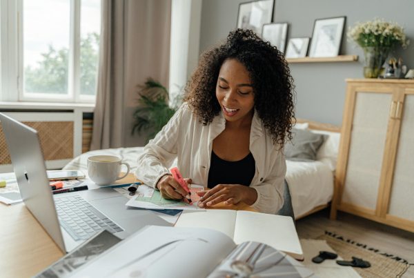 Pessoa estuda em ambiente acolhedor com laptop, caneca e materiais de apoio, representando foco e produtividade. A imagem sugere como a mentoria para MEI pode impulsionar organização e aprendizado contínuo.