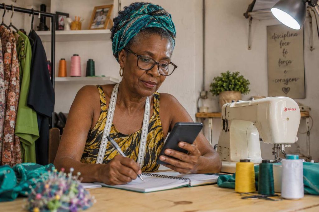 Mulher estudando bases teorias da Aliança Empreendedora em atelie de costura.