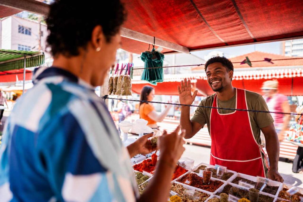 Cena de feira vibrante onde tecnologia social conecta empreendedores locais a clientes e oportunidades comerciais