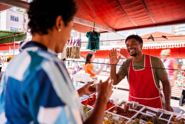 Cena de feira vibrante onde tecnologia social conecta empreendedores locais a clientes e oportunidades comerciais